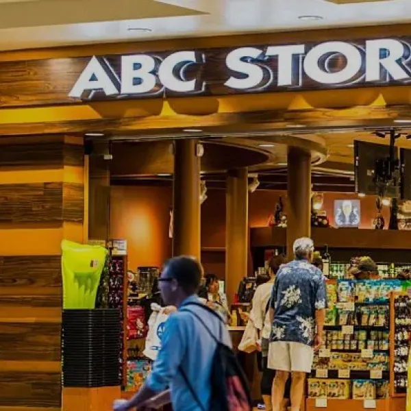 Entrance of ABC Stores with shoppers browsing shelves filled with snacks, drinks, and souvenirs