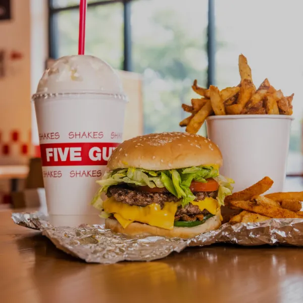 Five Guys meal with cheeseburger, seasoned fries, and creamy milkshake on restaurant table