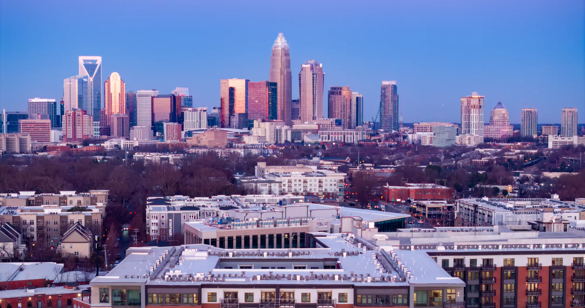 Charlotte skyline at dusk with prominent skyscrapers and surrounding low-rise apartment complexes