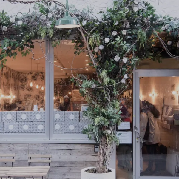 Charming café exterior with lush greenery framing entrance and cozy window seating area