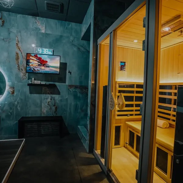 Private SWTHZ sauna suite featuring warm lighting and mounted flat-screen television