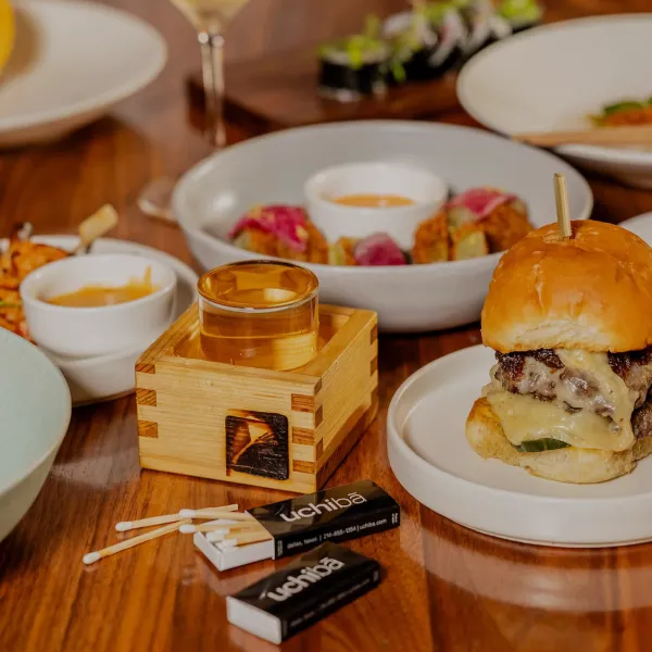 Gourmet cheeseburger with melted cheese, accompanied by assorted appetizers and craft cocktails