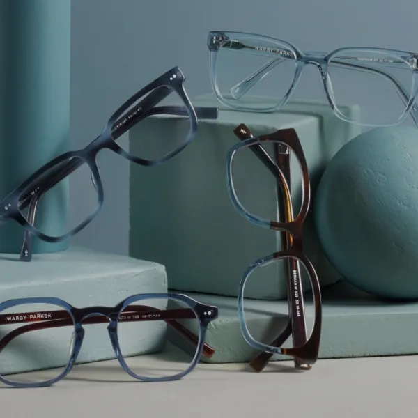 Stylish Warby Parker eyeglasses in assorted frame colors displayed against modern blue-toned background