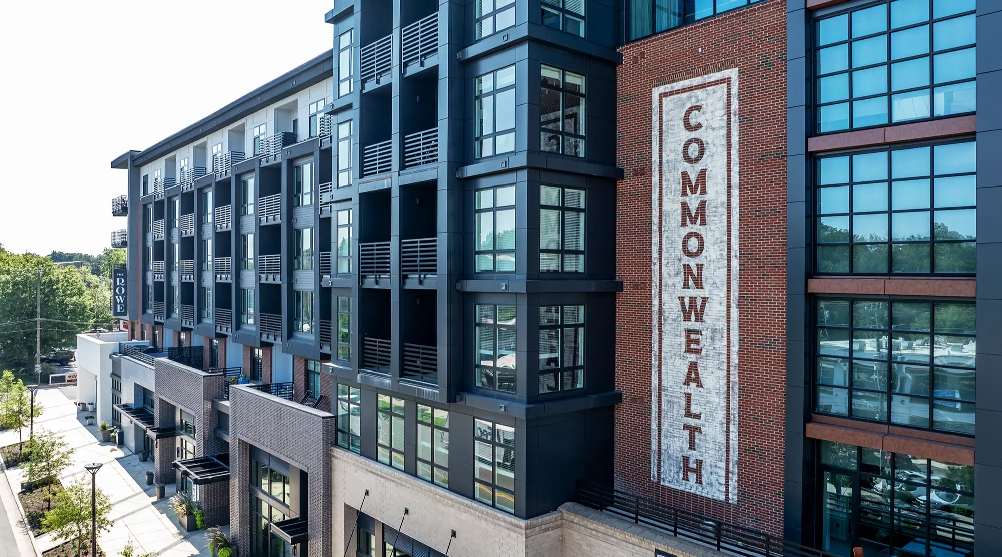 Modern apartment building with dark balconies and large windows beside a painted COMMONWEALTH sign