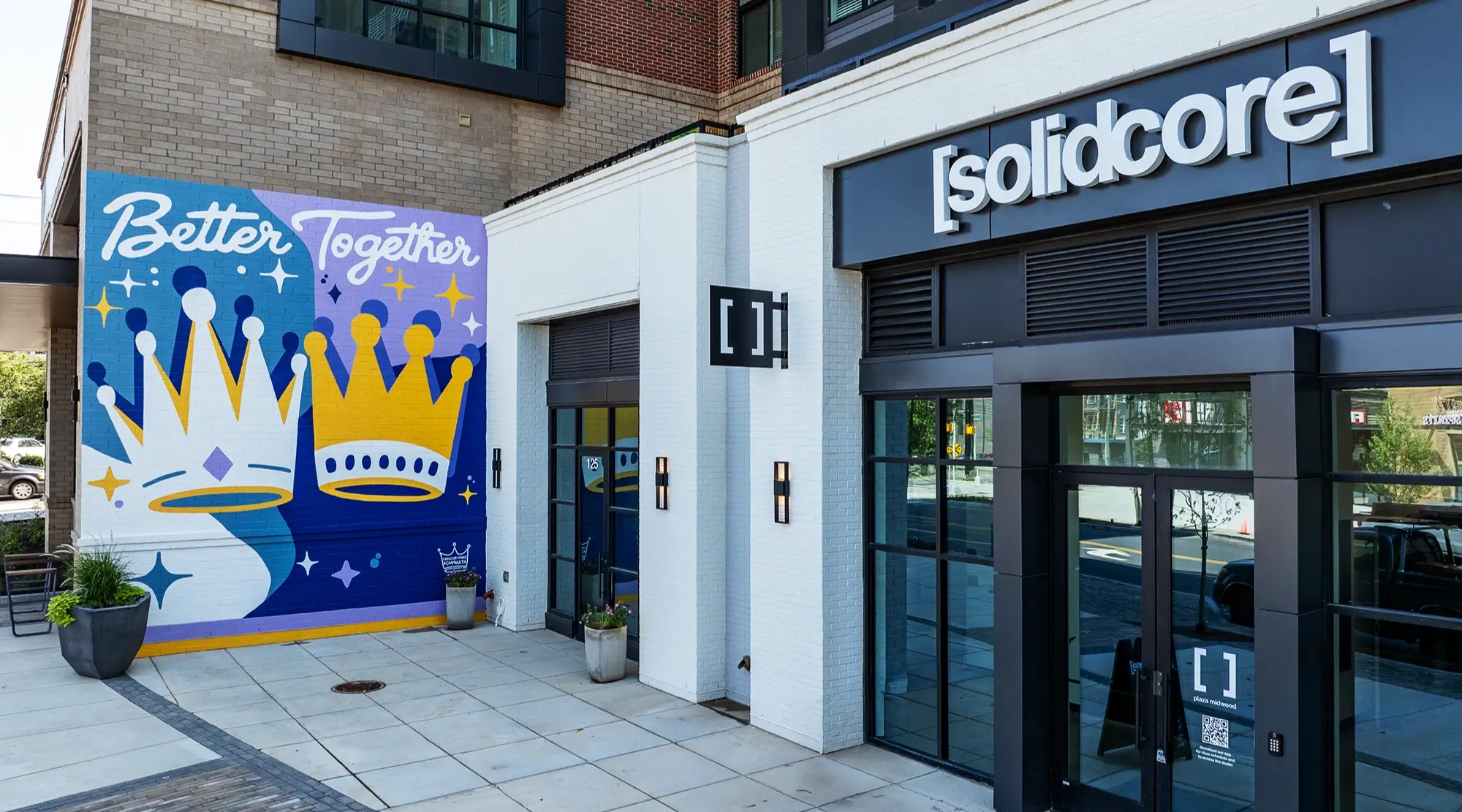 Colorful mural with crown illustrations and Better Together next to [solidcore] fitness entrance