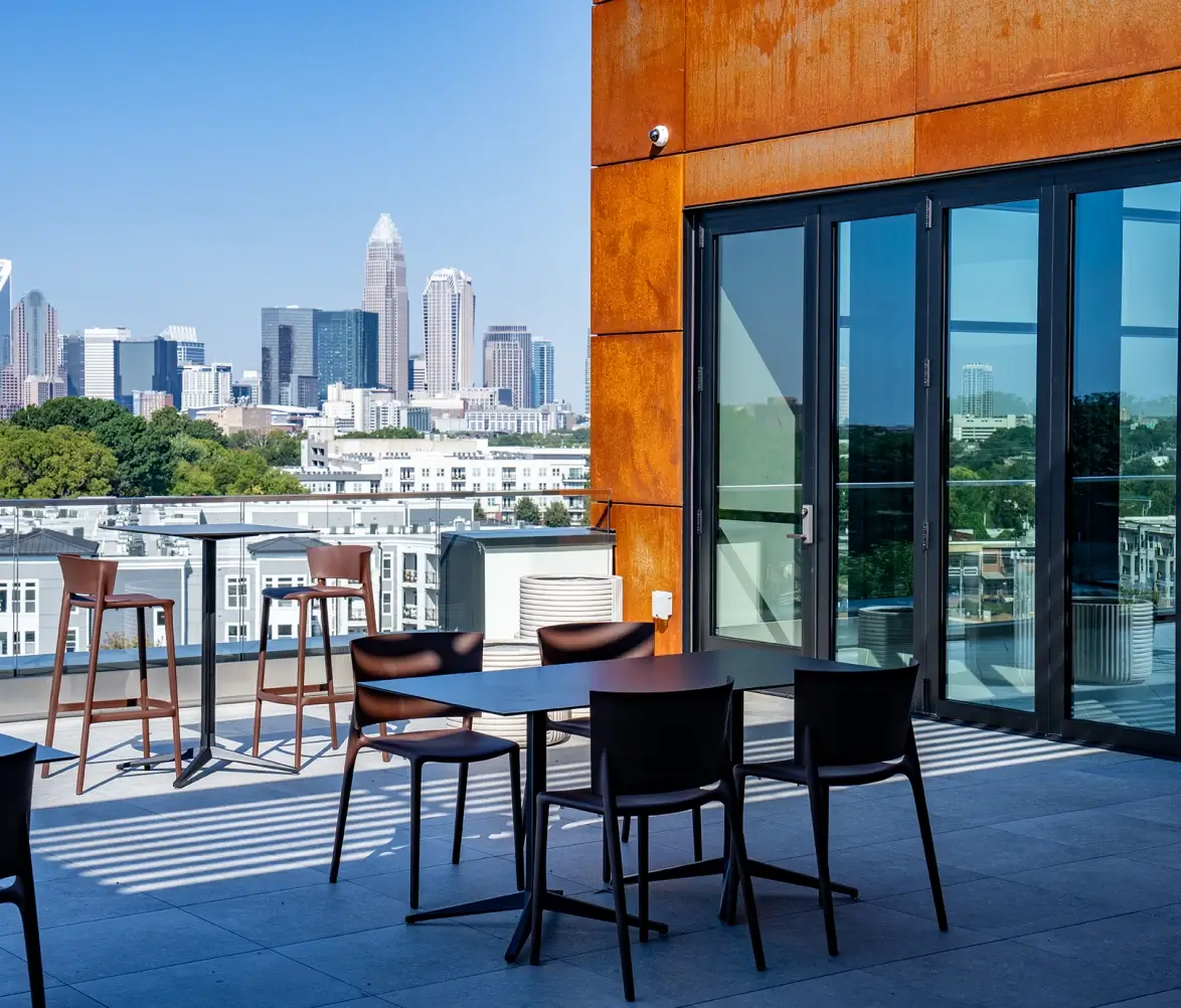 Rooftop patio with outdoor seating overlooking Charlotte skyline and modern glass building exterior