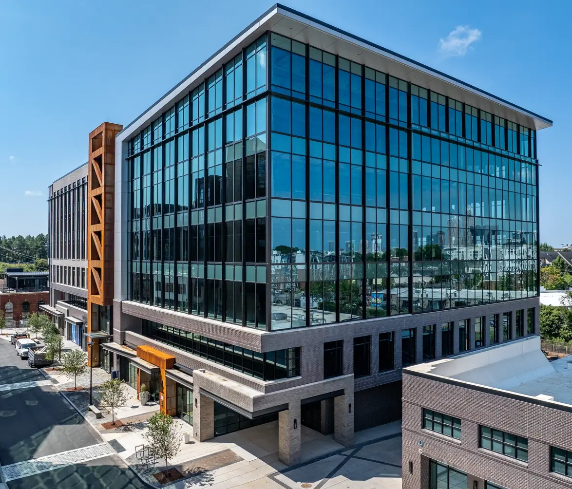 Sleek glass office building with reflective windows and orange accent framing modern entryway
