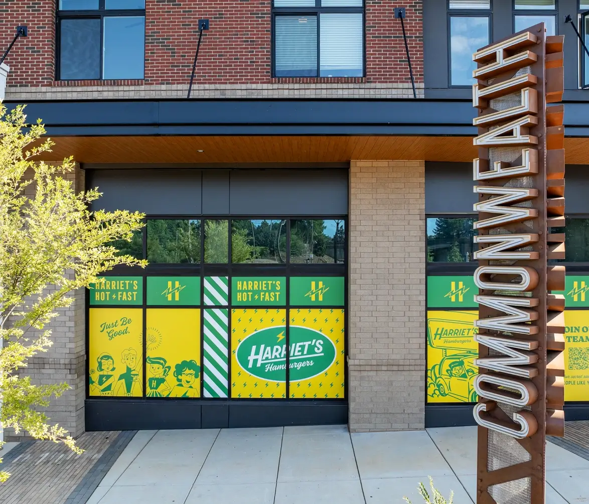 Harriet’s Hamburgers storefront with bold yellow signage and Commonwealth metal sculpture