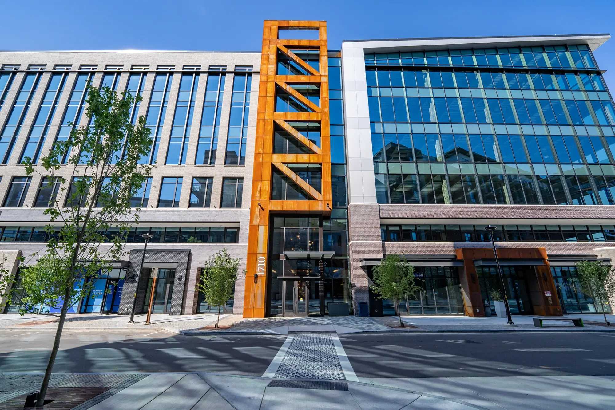 Front view of modern office building with glass façade and bright orange structural accent
