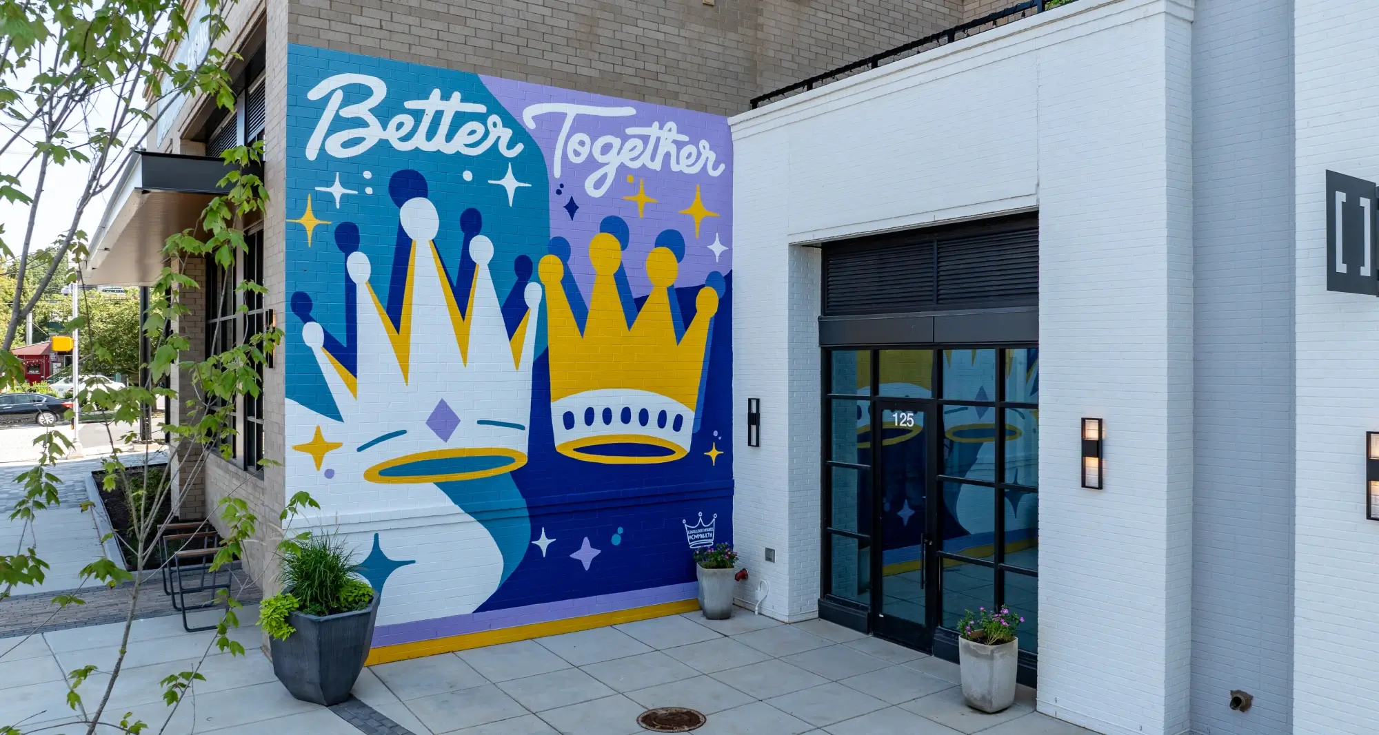 Colorful mural reading Better Together with crown designs beside retail entrance at 125 address