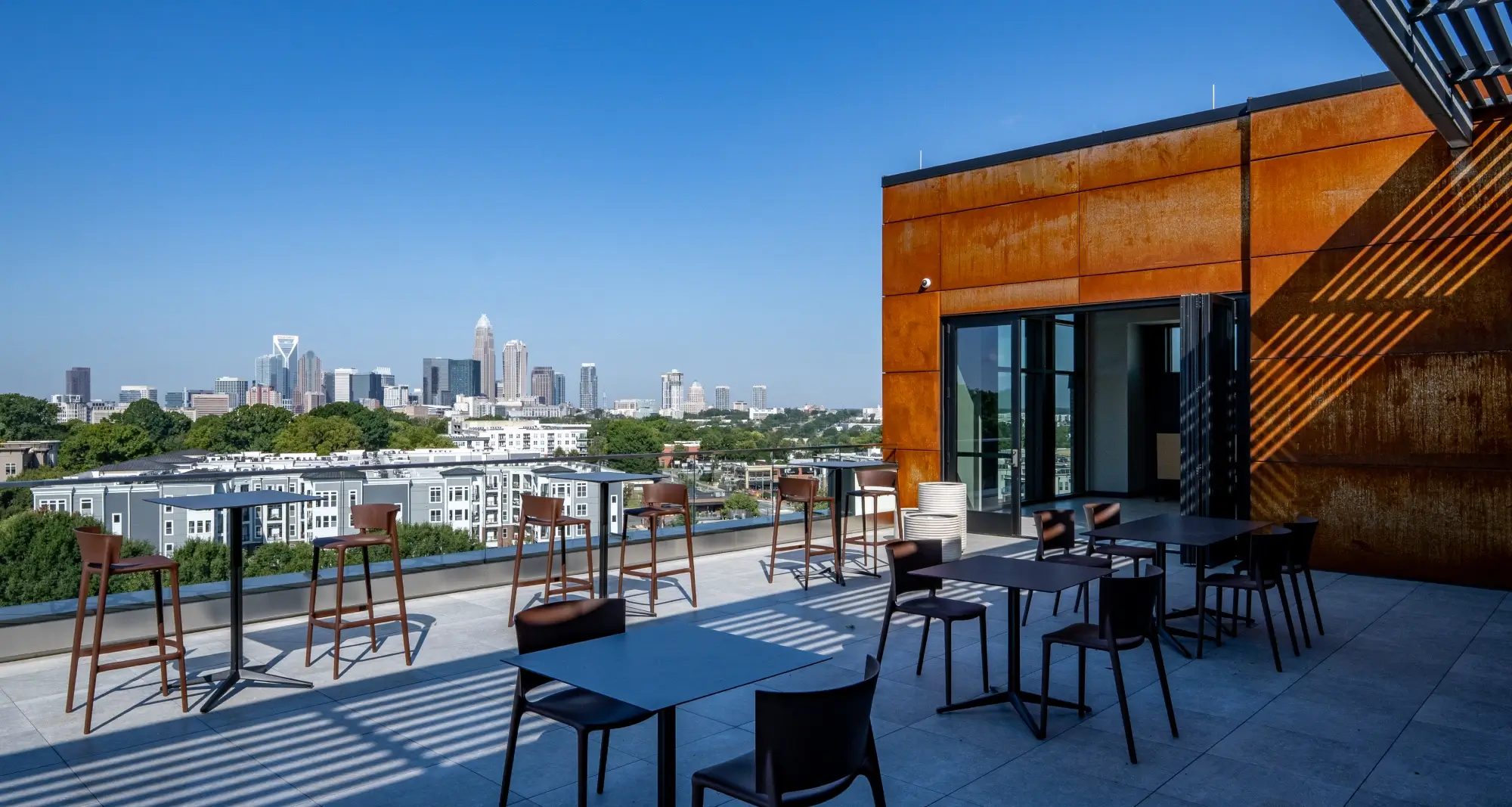 Rooftop lounge with rust-toned siding and panoramic views of uptown Charlotte skyline