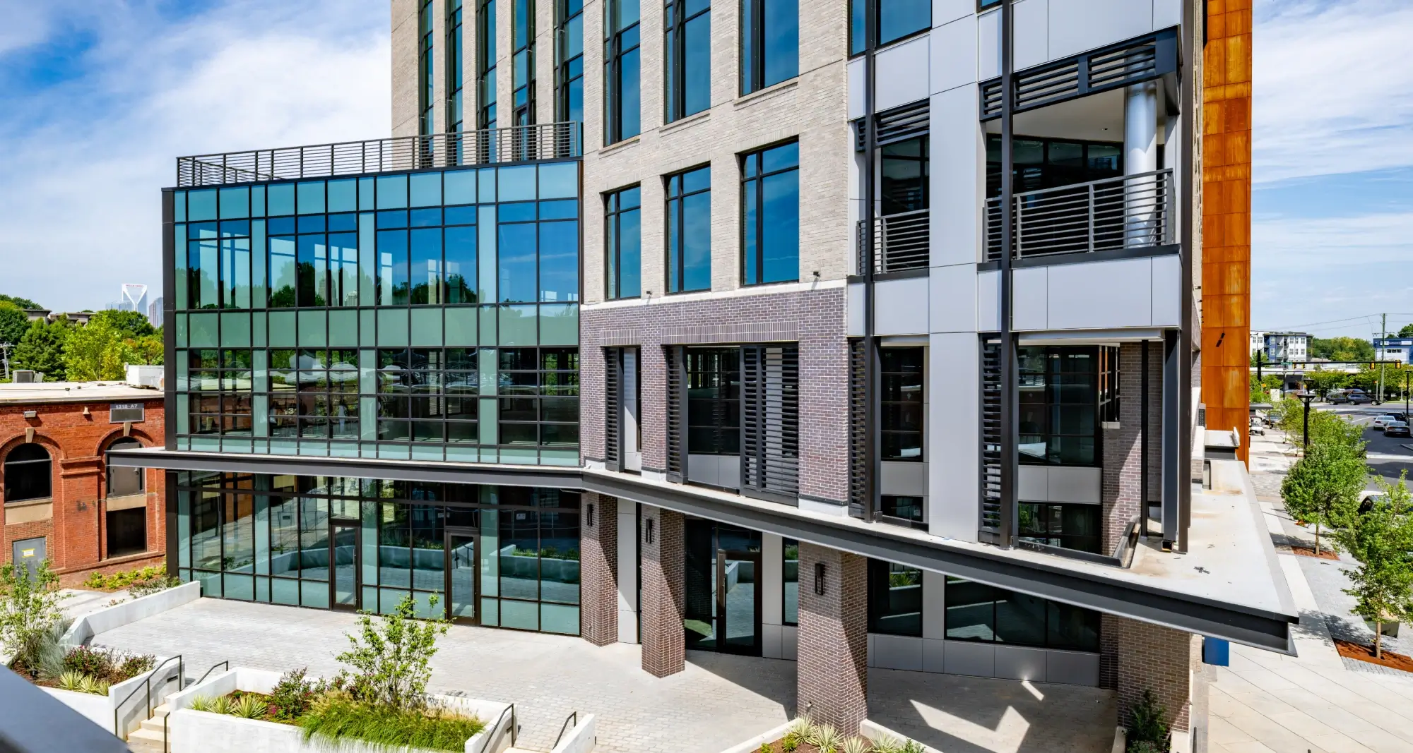 Modern office building corner with brick and glass materials above landscaped pedestrian walkway