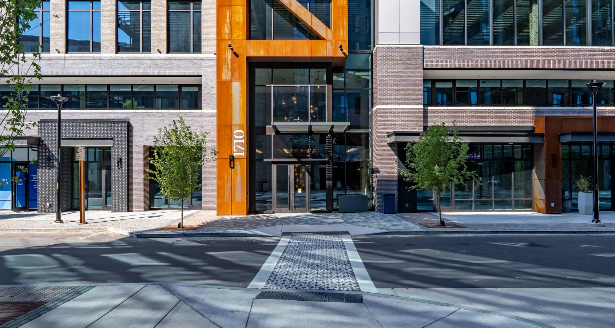 Close-up of Commonwealth building’s 1710 entrance with orange steel framing and reflective glass