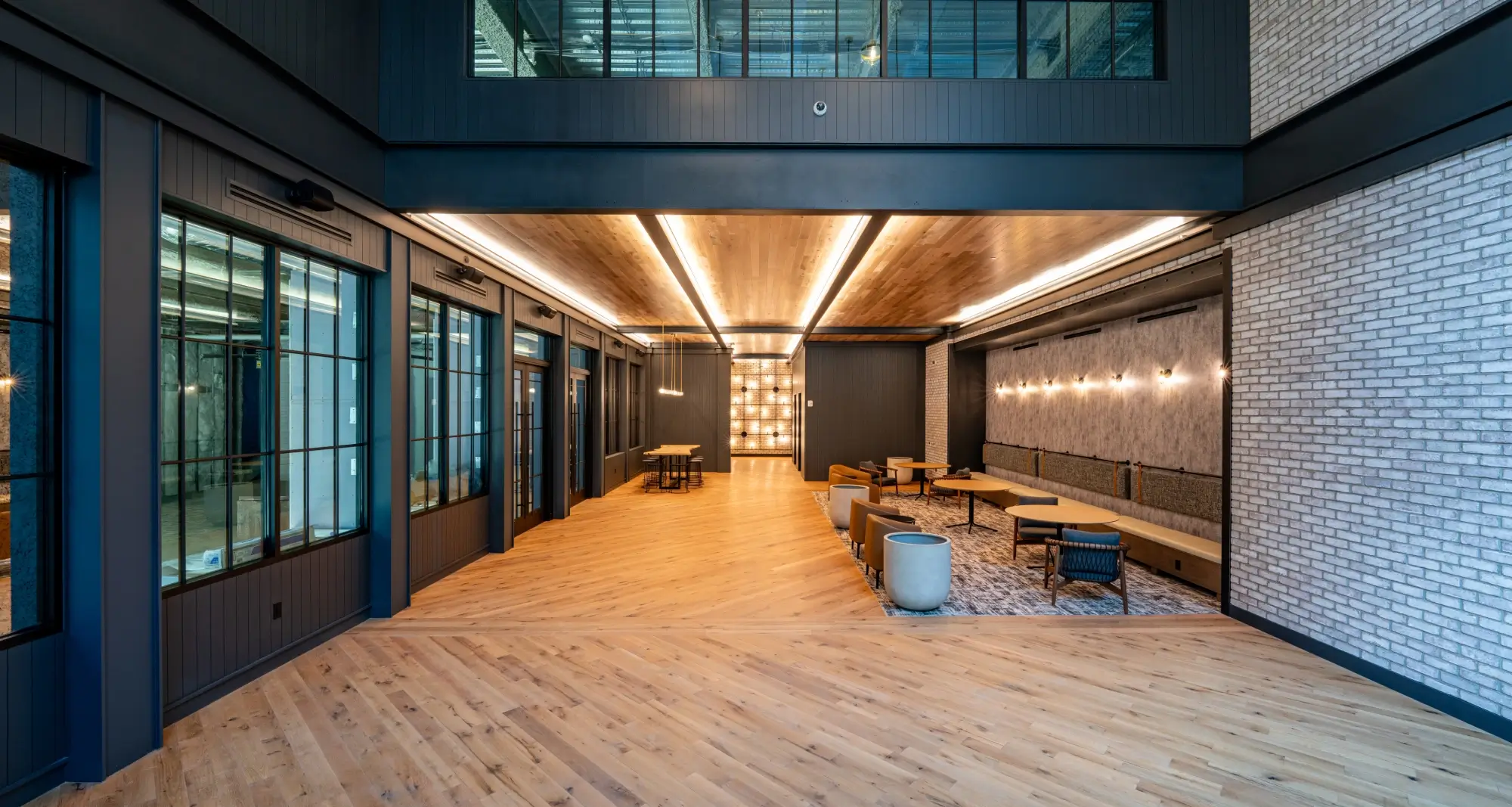 Stylish interior lounge space with wood floors, modern lighting, and industrial ceiling accents
