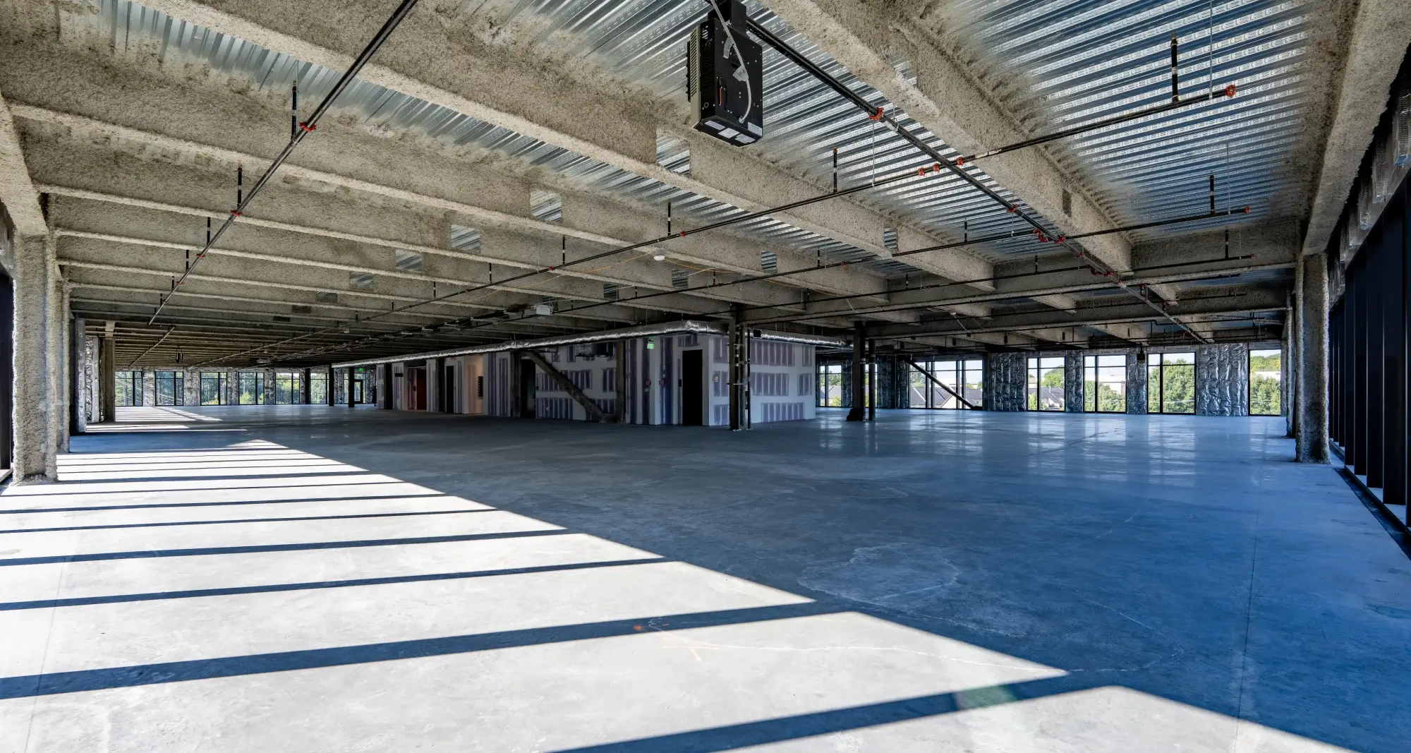 Unfinished commercial office floor with open layout, exposed ceilings, and concrete flooring