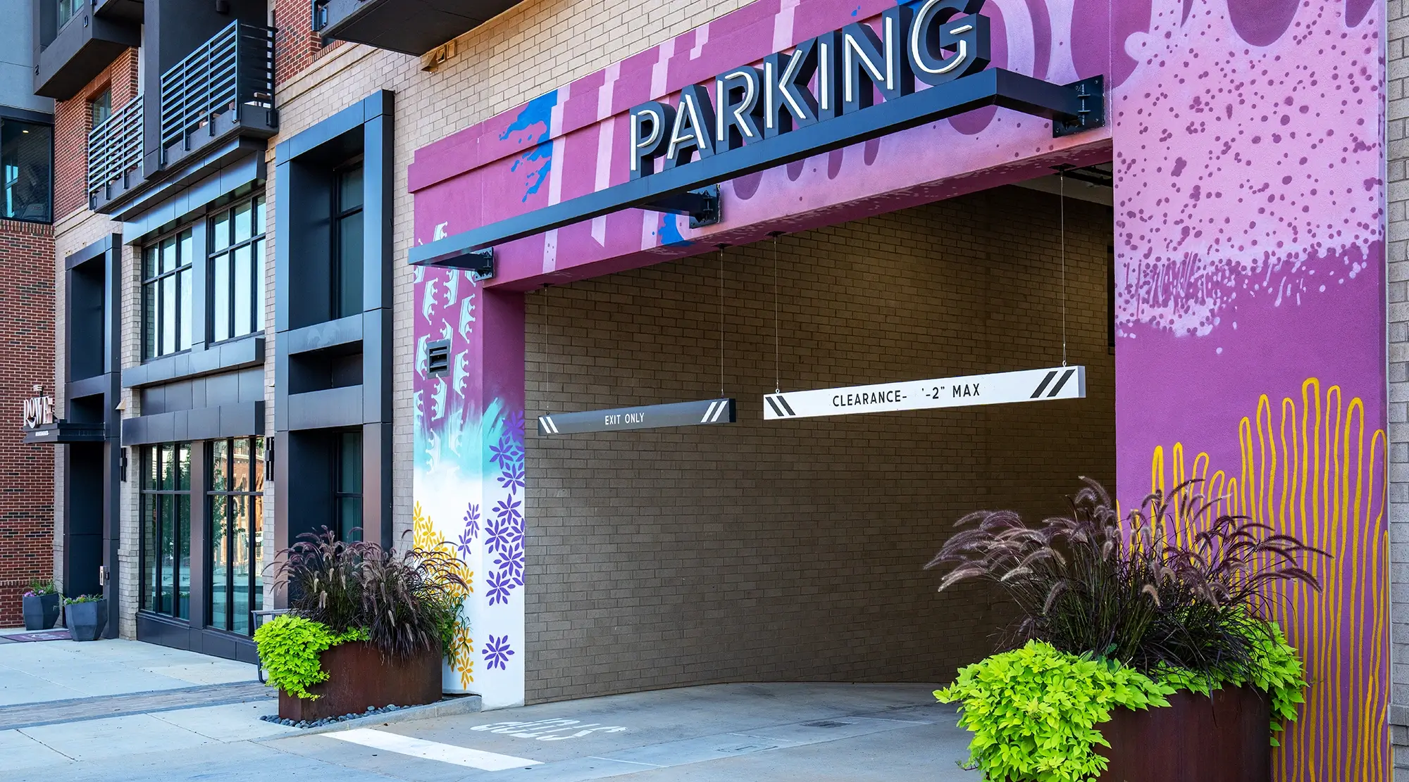 Parking garage entrance with colorful purple mural and bold signage reading clearance height